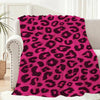 A vibrant pink leopard print flannel throw blanket draped over a light-colored sofa.