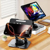 A 360° rotating carbon steel tablet stand is shown on a wooden desk with a laptop and a tablet in the background.