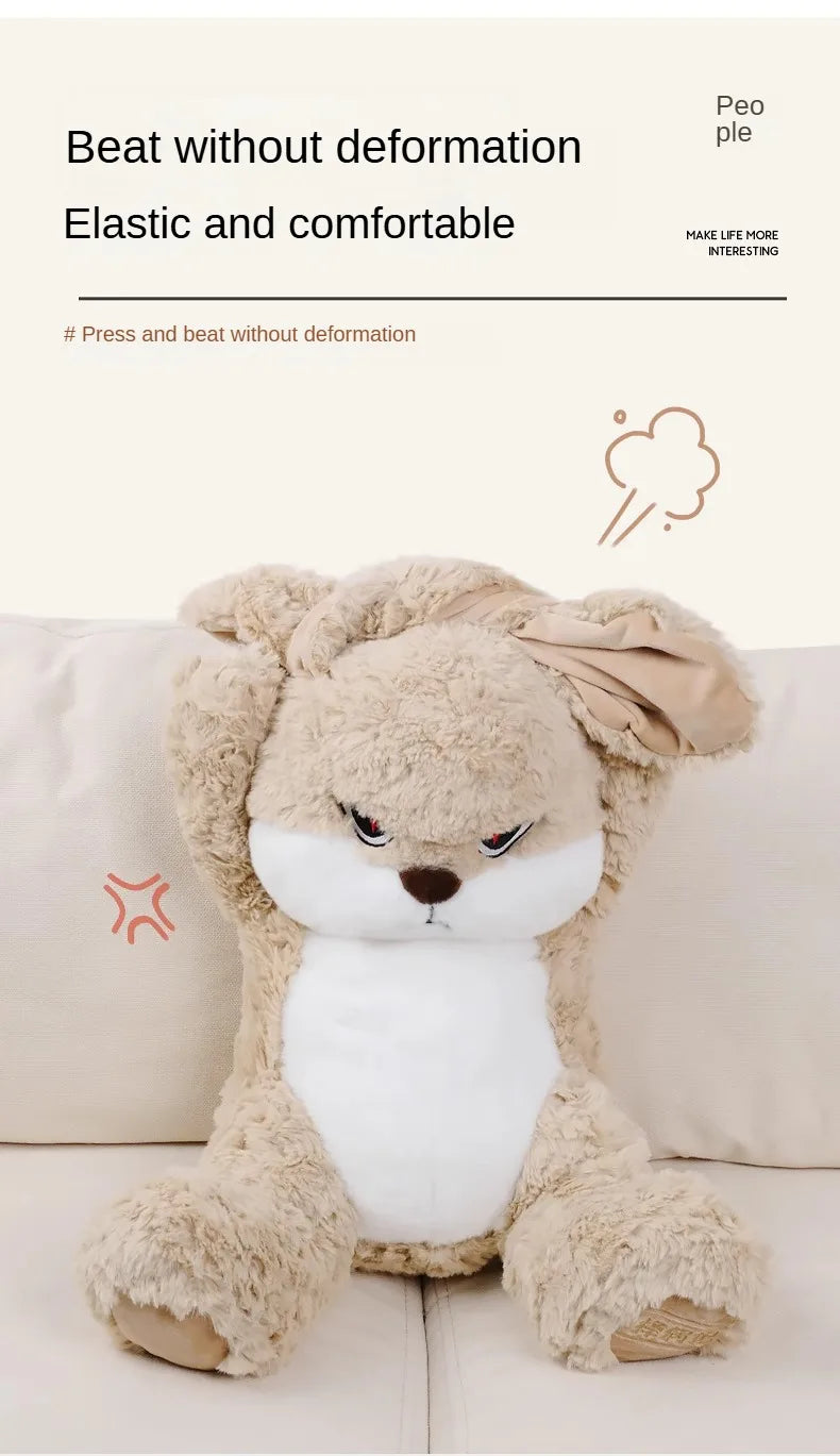 A fluffy, light brown rabbit plush toy with white accents sitting on a light-colored sofa.