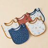 A collection of four cotton baby bibs in various colors and patterns laid out on a light background.