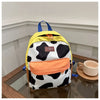 A yellow and black cow print backpack with blue straps resting on a wooden surface.