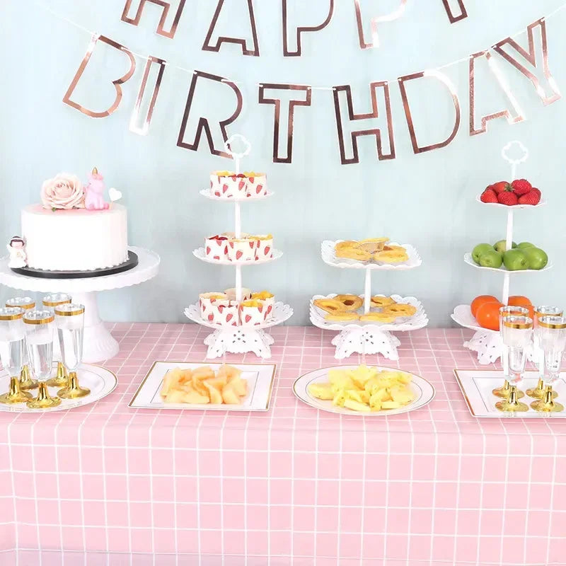 Rosa und goldene Geburtstagsparty-Dekoration mit mehrstöckigen Kuchen, Obst und Dekorationen auf einem Tisch.