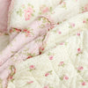 Close-up of a handcrafted cotton floral patchwork quilt featuring pink and white fabric with embroidery.
