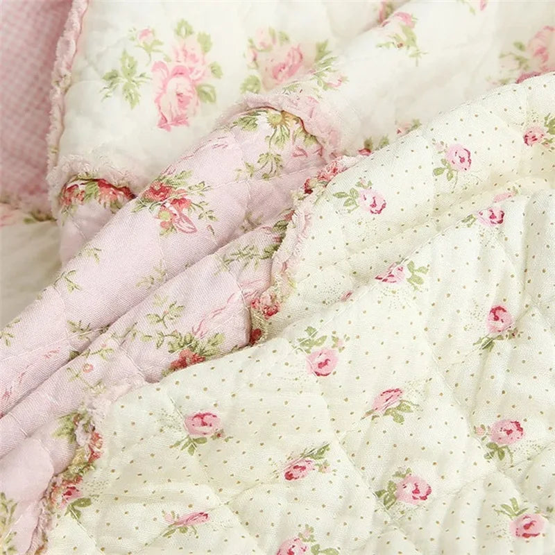 Close-up of a handcrafted cotton floral patchwork quilt featuring pink and white fabric with embroidery.