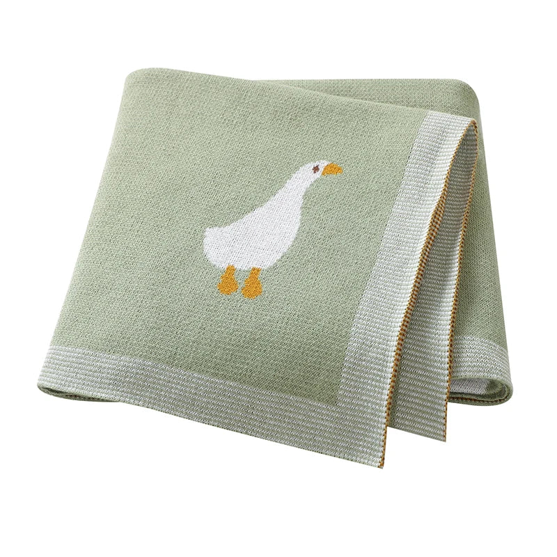 A light green soft cotton baby swaddle blanket featuring a white cartoon duck print.