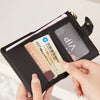 A hand is opening a black crocodile-embossed PU leather bifold wallet to display several credit cards.