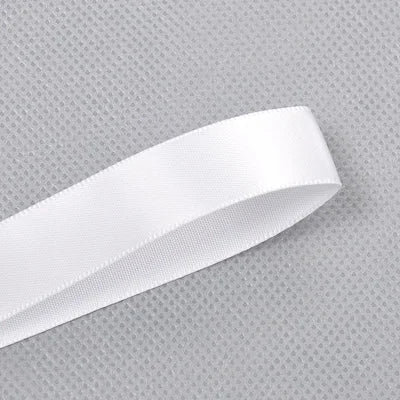 A roll of white double face satin ribbon against a gray textured background.