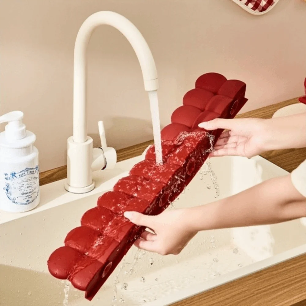 Hände spülen einen roten Silikonsink-Schutzabfluss unter fließendem Wasser in einer Badewanne.
