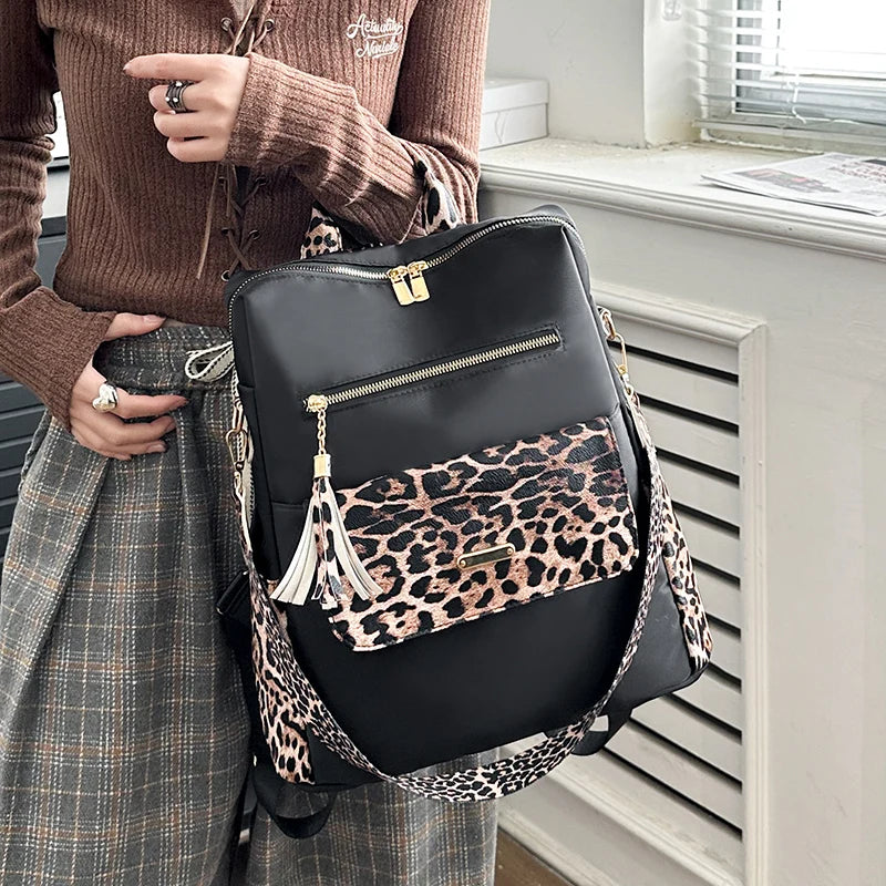 Ein schwarzer Leopardenmuster-Rucksack für Mode und Reisen neben einer Person mit braunem Pullover und karierter Röcke.