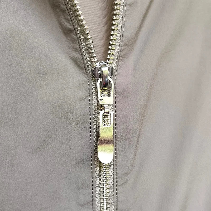 Close-up of a silver metal zipper pull replacement slider on a gray fabric garment.