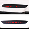 Black carbon fiber brake light sticker with red markings applied to a white car surface.