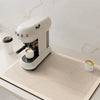 A white Meg coffee grinder sits on a beige quick-dry diatom mud absorbent counter mat.