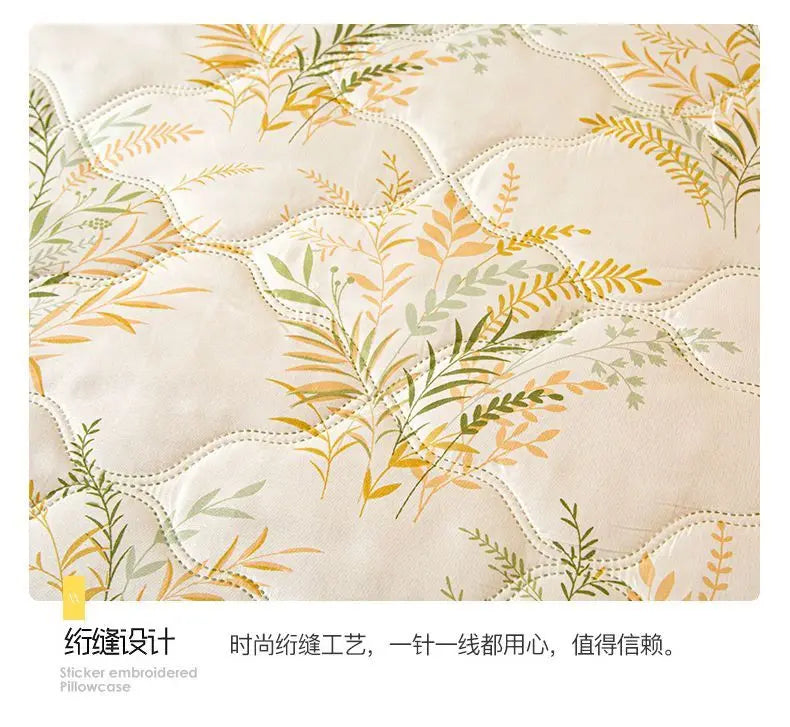 A close-up of a light beige fabric featuring an embroidered pattern of olive and sage green leaves on a quilted surface.
