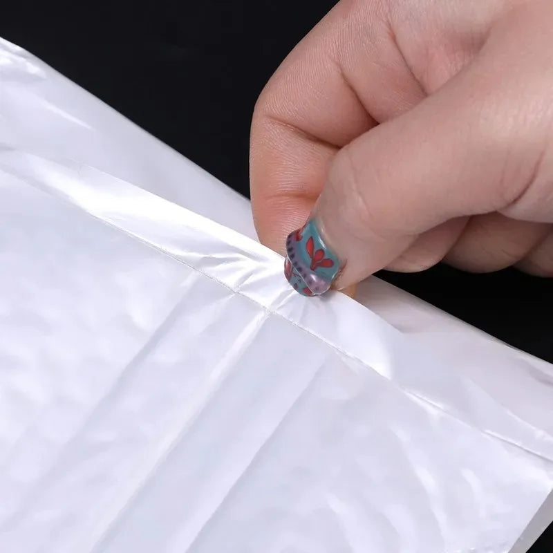A hand is sealing a white padded bubble mailer with a self-seal closure.