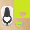 A white heart-shaped paper punch tool is shown next to a green card with a heart outline and a measurement indicator.