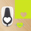 A white heart-shaped paper punch tool is shown next to a green background with a heart outline and a measurement of 1 inch.
