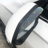 A white car rearview mirror with a clear lens and a decorative rhinestone rain guard covering the top edge.