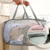 A person is holding a gray folding mesh laundry basket with handles, showing the interior filled with folded clothes.