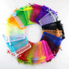 A circular arrangement of colorful organza drawstring jewelry gift bags in various shades of green, yellow, pink, purple, and