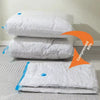 White vacuum storage bags with a hand pump stacked and laid out on a white surface.