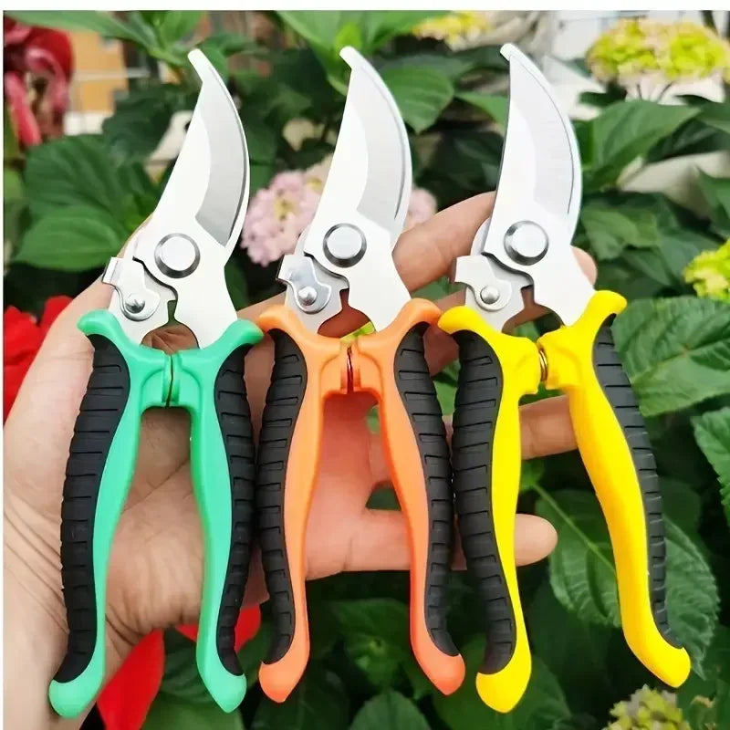 A hand holds three stainless steel bypass pruning shears in green, orange, and yellow grips against a green plant background.
