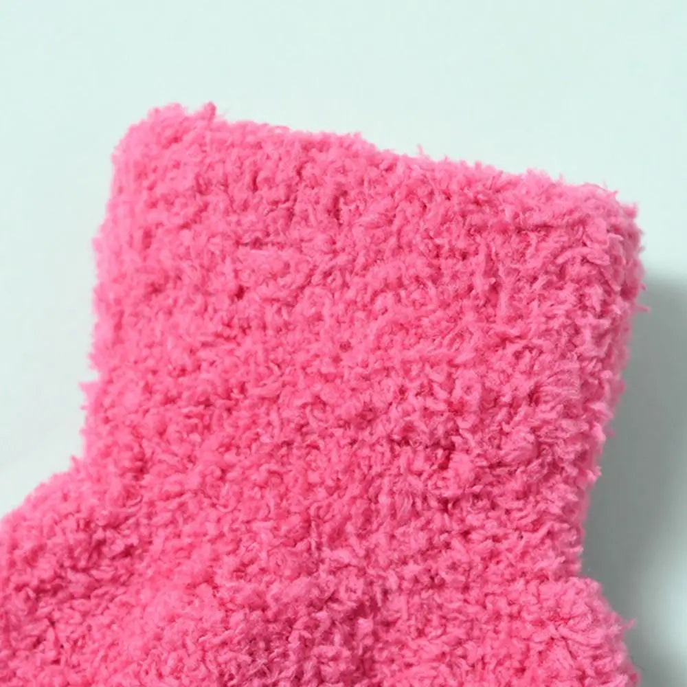 A close-up of bright pink, fluffy plush winter gloves for kids.