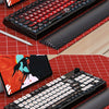 A close-up view of a pudding keycaps set keyboard and a matching laptop, displayed on a red grid background.