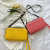 A pink and yellow waterproof passport organizer wallet with black strap lies on a white fabric background.