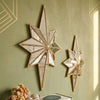 A gold-framed octagonal star resin wall mirror mounted on a muted green textured wall.