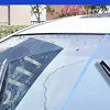 Close-up view of a white car's glass showing water beading, demonstrating hydrophobic rain repellent spray application.