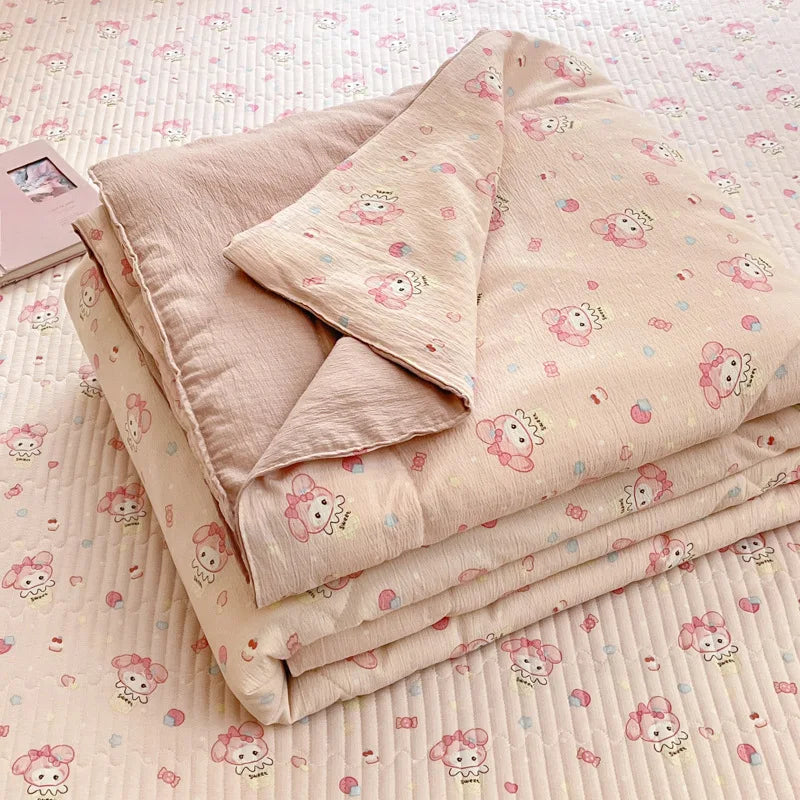 A stack of light pink cartoon pattern kids lightweight summer quilts lying on a textured white surface.