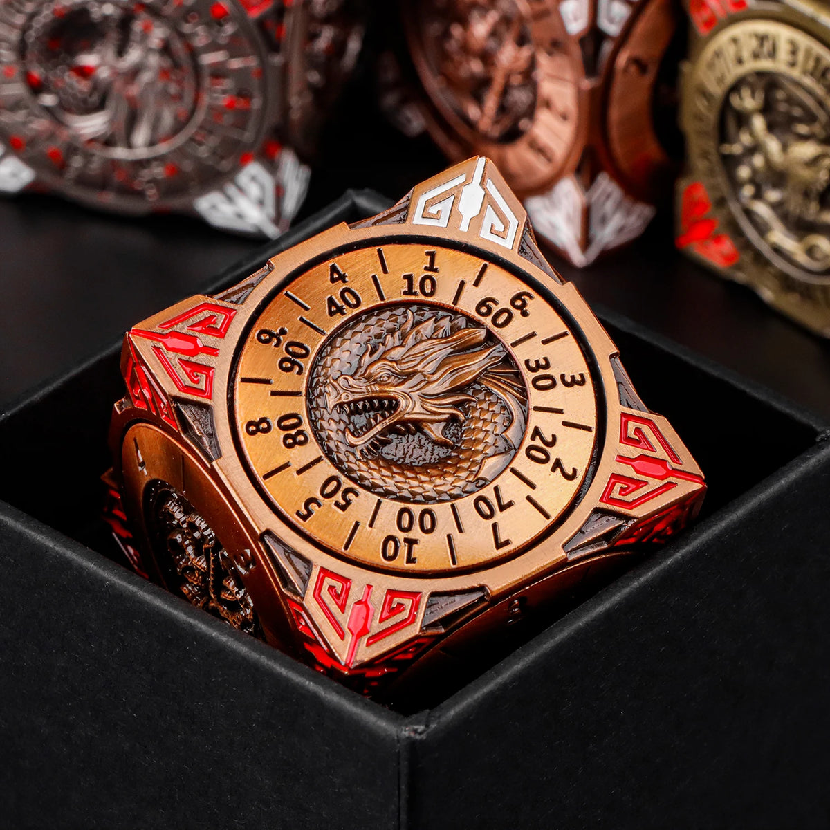 A close-up of a premium metal spinner dice cube with a dragon design, resting in a black gift box.