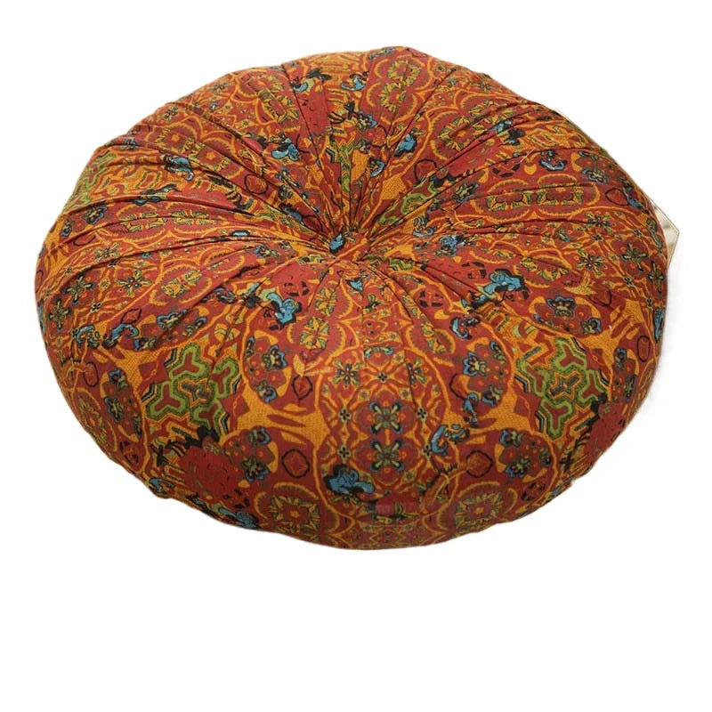 A round, textured floor cushion in a vibrant orange and rust pattern with blue accents.