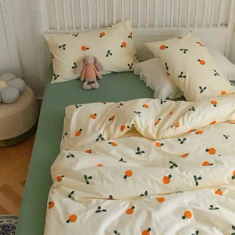 A light yellow bedding set with a white duvet cover and pillows featuring an orange and green floral pattern.