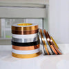 A stack of various colored self-adhesive waterproof tile gap sealing tape rolls on a white surface.