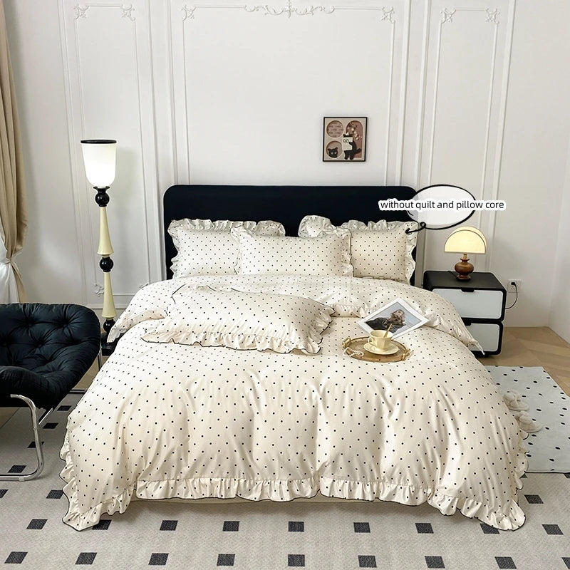 A beige duvet cover set with black polka dots and ruffled edges displayed on a bed.