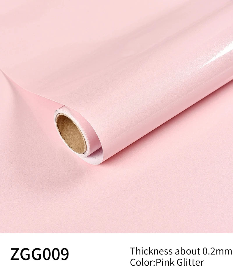 Roll of pink glitter peel-and-stick vinyl contact paper shown rolled up on a light pink surface