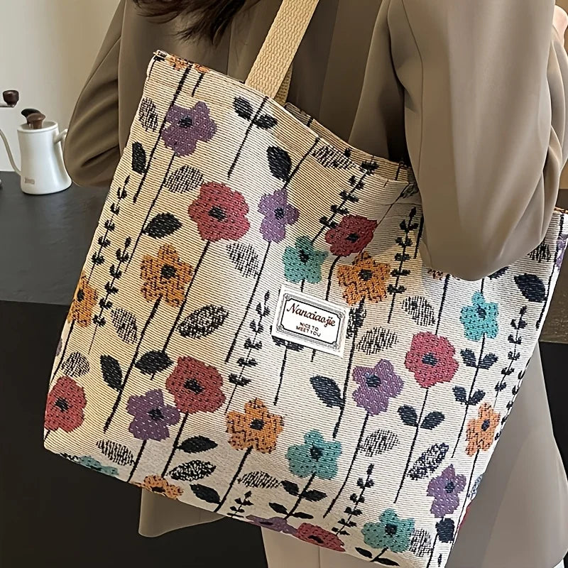 A beige corduroy tote bag with a floral pattern is carried by a person.