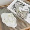 A silver cloud-shaped jewelry tray with a pearl necklace is displayed on a white tray and next to its packaging.
