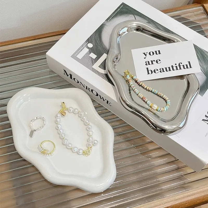 A silver cloud-shaped jewelry tray with a pearl necklace is displayed on a white tray and next to its packaging.