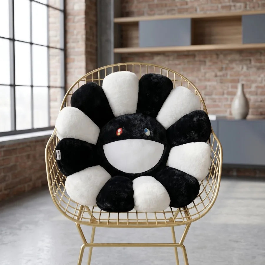 A black and white sunflower plush cushion with a smiling face is displayed in a gold wire chair.