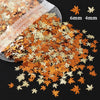 A pile of shiny holographic star sequins in shades of orange and gold scattered on a dark surface.