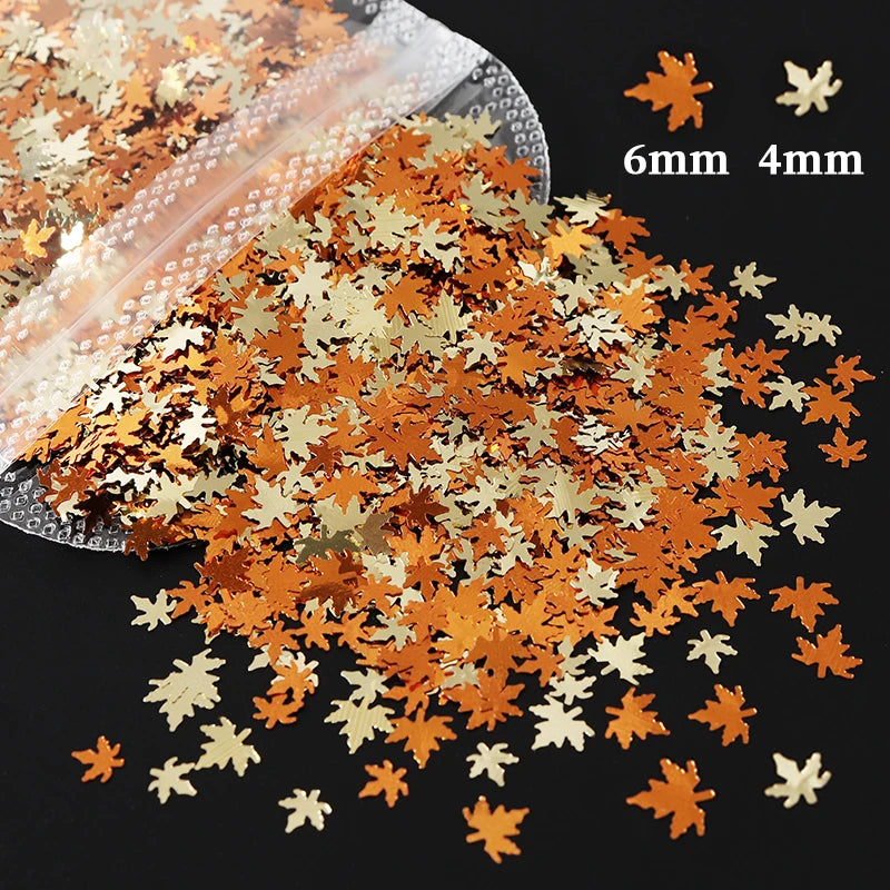A pile of shiny holographic star sequins in shades of orange and gold scattered on a dark surface.