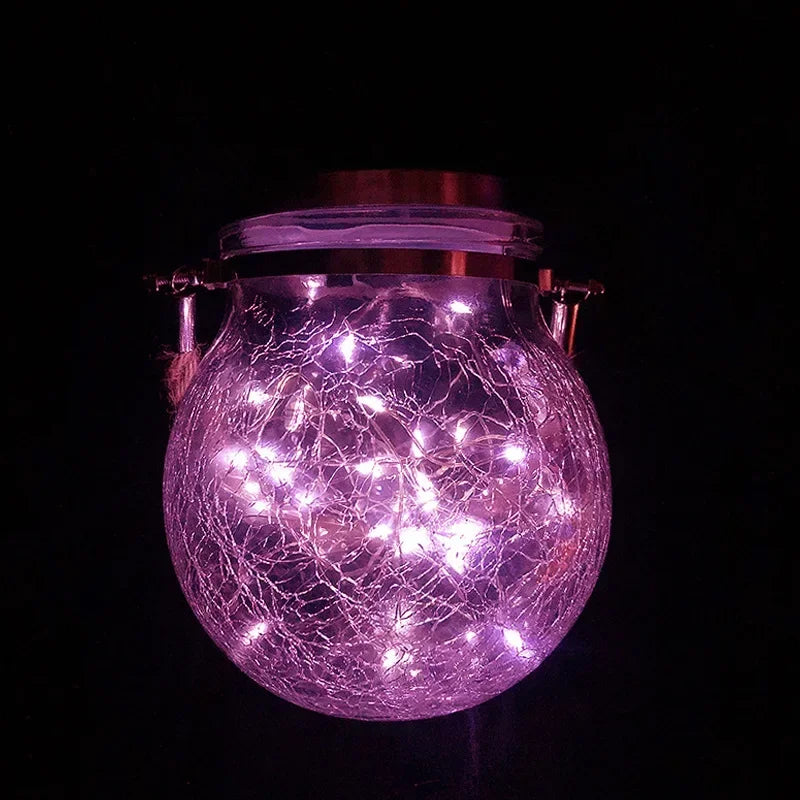 A glowing purple crackle glass solar lantern illuminating a spherical shape against a dark background.