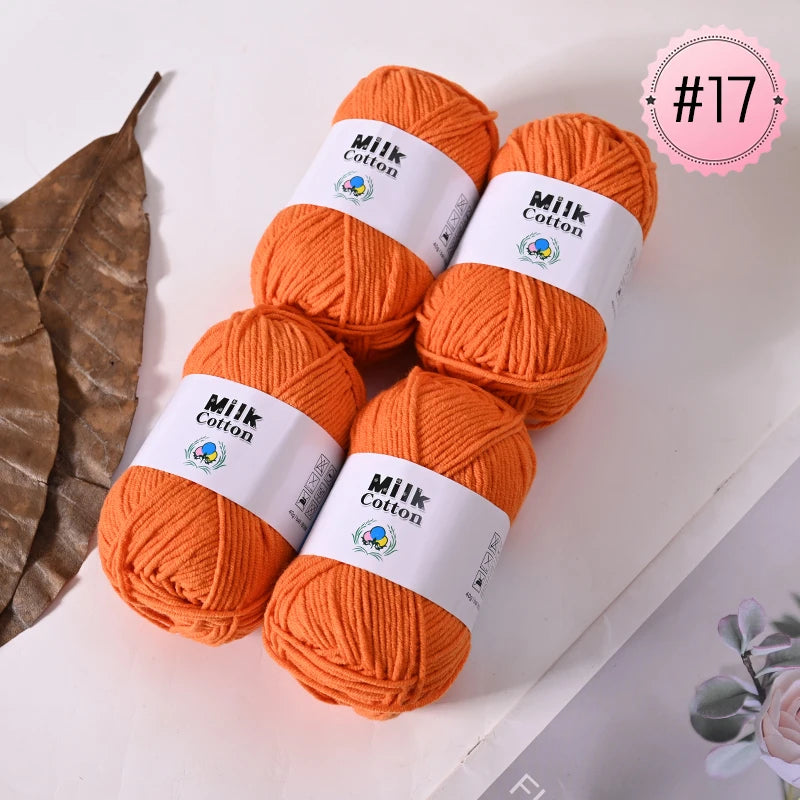 A collection of bright orange Milk Cotton yarn skeins displayed on a white surface.