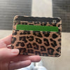 A hand holds a leopard print PU leather card wallet with a green card inside.