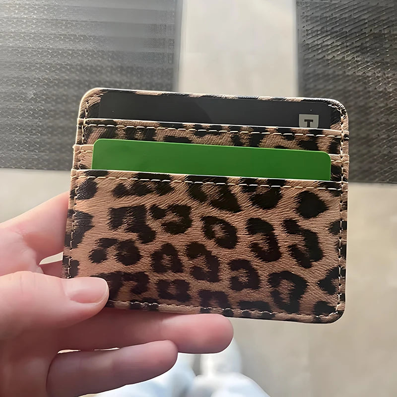 A hand holds a leopard print PU leather card wallet with a green card inside.