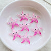 Pink glitter starfish resin charms arranged in a white bowl for crafting and jewelry making