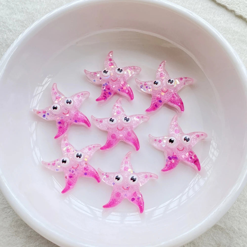 Pink glitter starfish resin charms arranged in a white bowl for crafting and jewelry making
