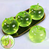 A green apple fruit shape squeeze toy for stress relief is displayed on a dark tray with a hand holding one.